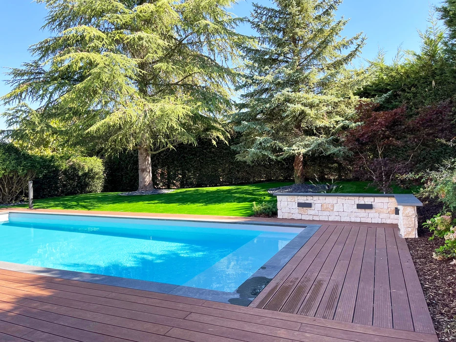 Piscine rectangulaire extérieure aux eaux turquoise, entourée d'une terrasse en lames de bois composite IPE