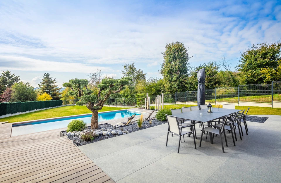Homme en polo bleu installant une clôture métallique extérieure, portant des gants de protection rouges