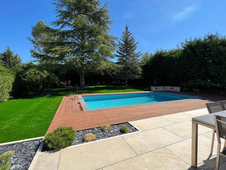 Piscine rectangulaire extérieure avec margelles blanches et plage en bois composite IPE