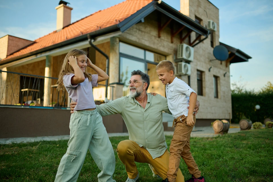 Jardin résidentiel avec clôture en bois horizontale neuve, bordure de plantation fraîchement aménagée avec arbustes taillés en boule, massifs floraux et paillis
