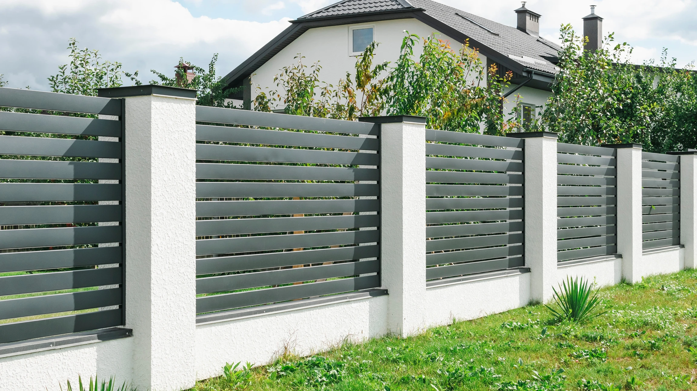 Portail contemporain à double vantaux en bois horizontal avec piliers en briques, intégré dans clôture assortie