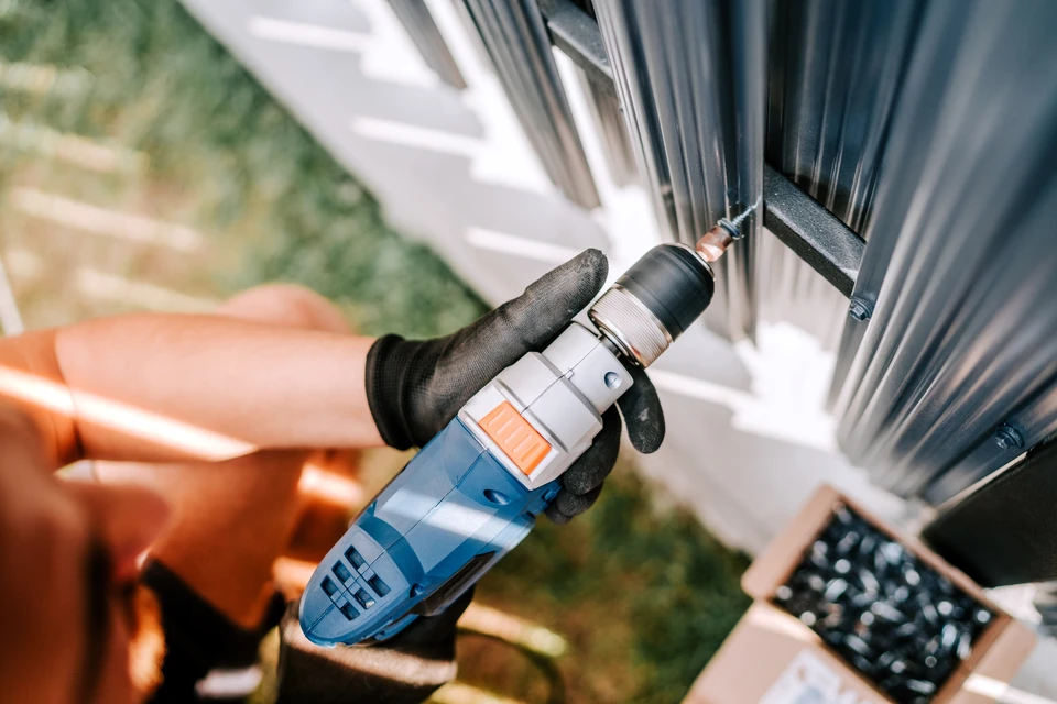 Un homme au chapeau dur, debout sur les marches, inspectant le toit de la maison