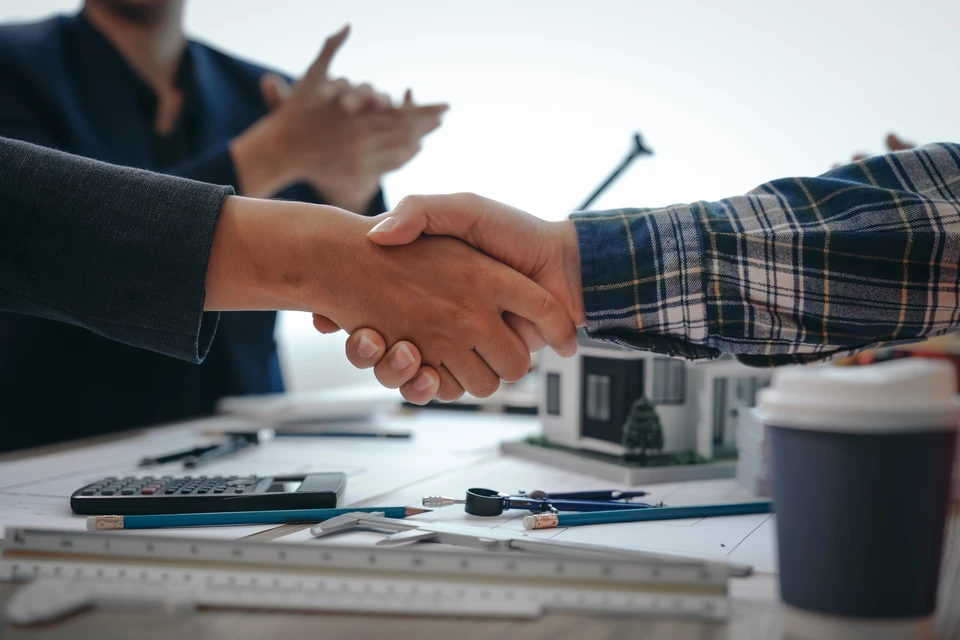 Professionnel en chemise bleue tenant une sphère verte végétale au-dessus de plans architecturaux