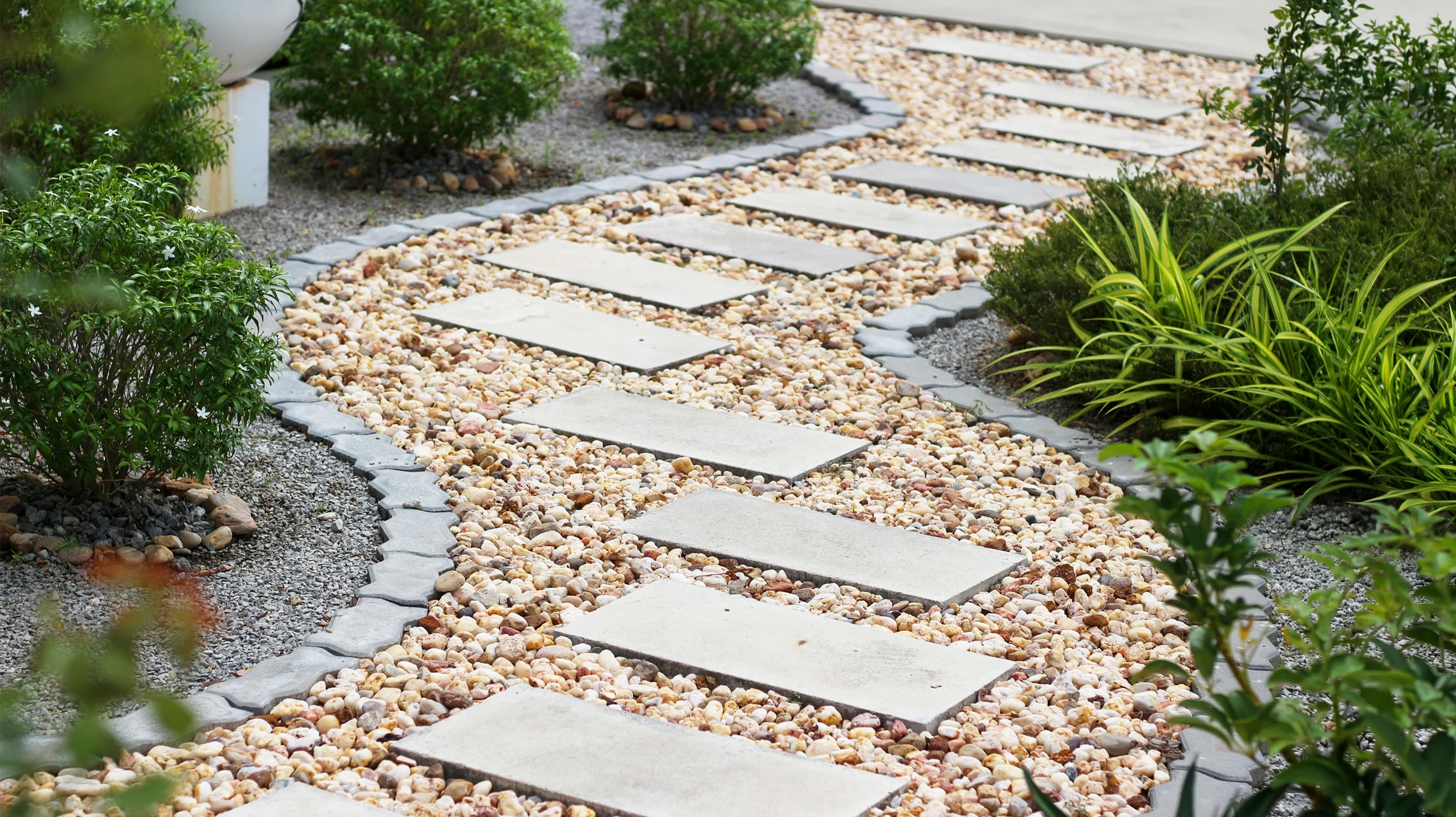 Photographie d'un jardin luxe complètement aménagé montrant un projet d'aménagement extérieur haut de gamme réalisé par l'entreprise. La scène doit inclure plusieurs éléments témoignant du savoir-faire complet : une terrasse pavée en beau matériau, une piscine en béton avec eau claire, une zone de plantations paysagères bien structurées, possiblement un portail ou une clôture élégante. Le tout doit être photographié dans des conditions d'éclairage naturel optimal, en jour ensoleillé, montrant l'harmonie et la qualité professionnelle du projet fini. La composition doit être généreuse et évocatrice de luxe et de professionnalisme.