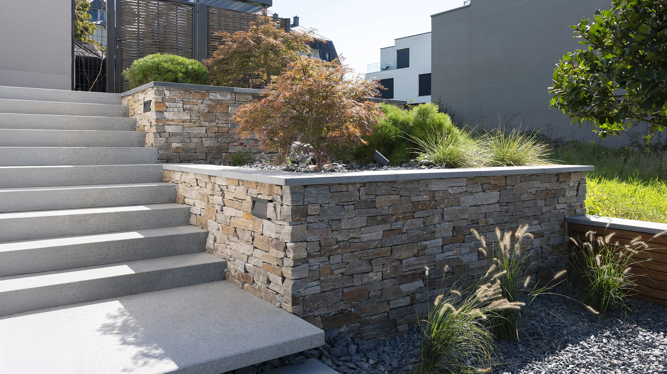 Entrée résidentielle avec escalier béton, rampe métallique décorative et porte d'entrée moderne