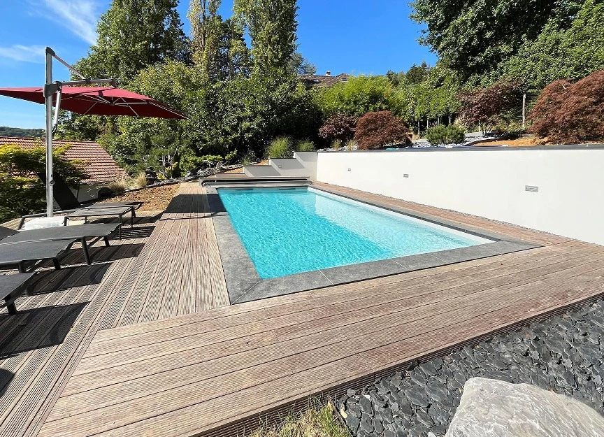 Piscine rectangulaire extérieure dans cour privée résidentielle avec transats en résine tressée
